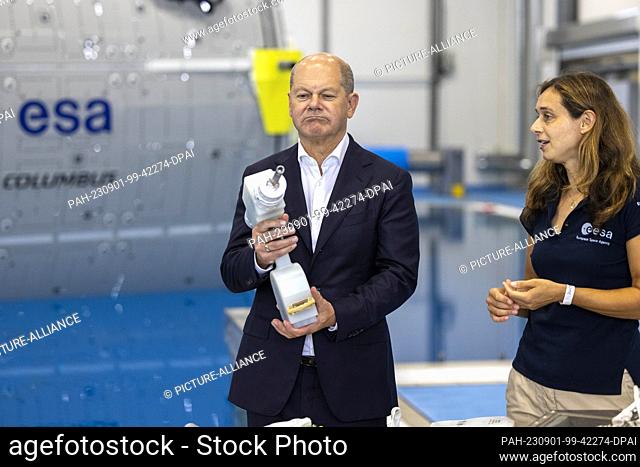 01 September 2023, North Rhine-Westphalia, Cologne: German Chancellor Olaf Scholz (SPD) has an ESA employee explain a cordless screwdriver that is part of the...