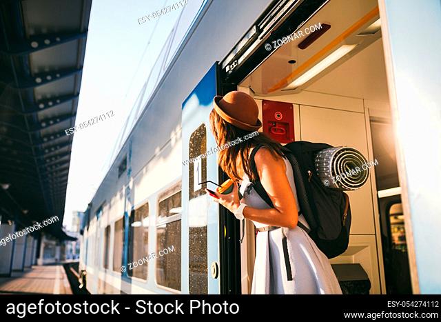 Woman peeking out train. Woman railway station. Young happy woman pulling face out train door looking for somebody railway station. Travelling
