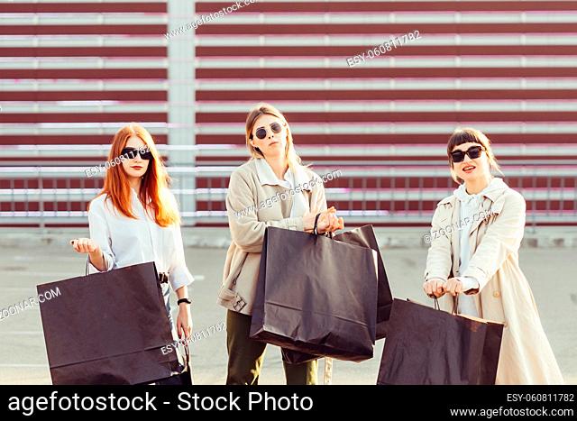 Young happy women with shopping bags walking on street