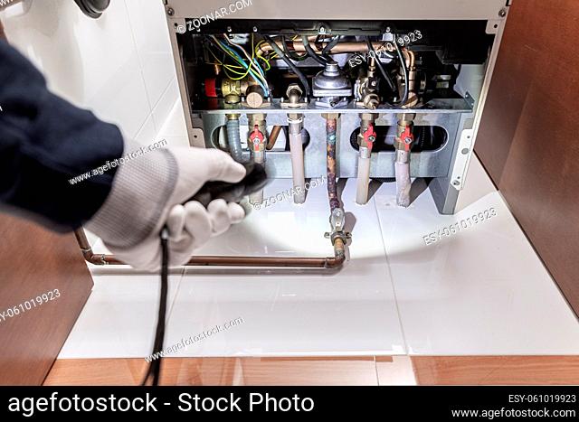 Technician inspecting a gas heater or heating boiler in a house. Maintenance concept