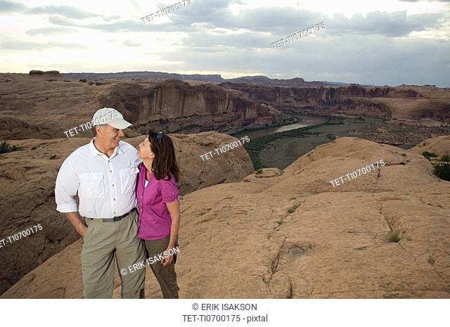 Couple smiling at each other on rock formation