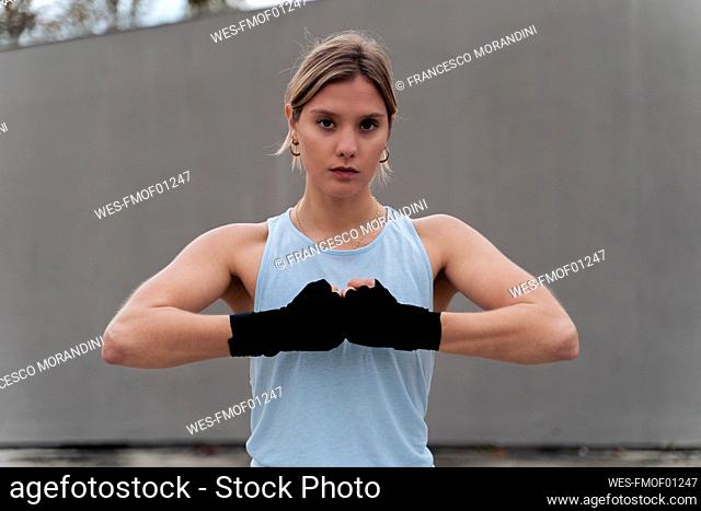 Sportswoman with bandage wrapped hand standing against wall