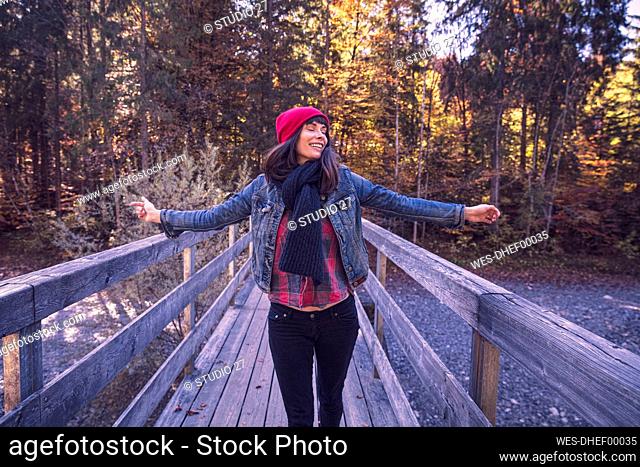 Woman wearing red woolly hat and denim jacket on a bridge in autumn