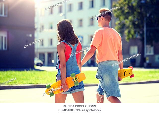teenage couple with skateboards on city crosswalk