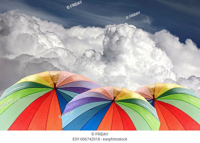 Rainbow umbrella on a background of the cloudy sky