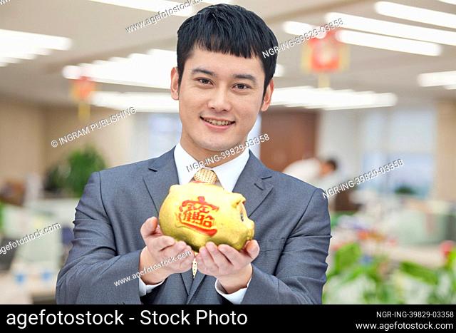 Young business man holding Chinese piggy bank, portrait