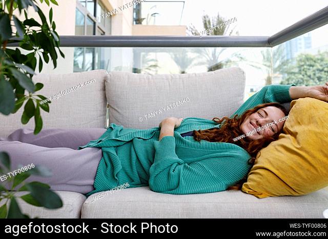 Smiling woman lying on sofa at home