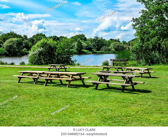 Some picnic tables with a lake and trees behind