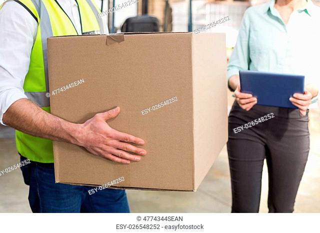 Close up of a warehouse worker carrying box in a large warehouse
