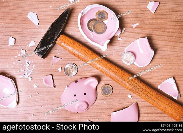 broken Piggy bank smashed into pieces with hammer and small or loose change euro coins