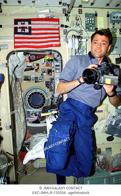 Astronaut Jeffrey S. Ashby, STS-100 pilot, prepares to document activity of his shuttle crew mates as well as members of the Expedition Two crew (out of frame)...