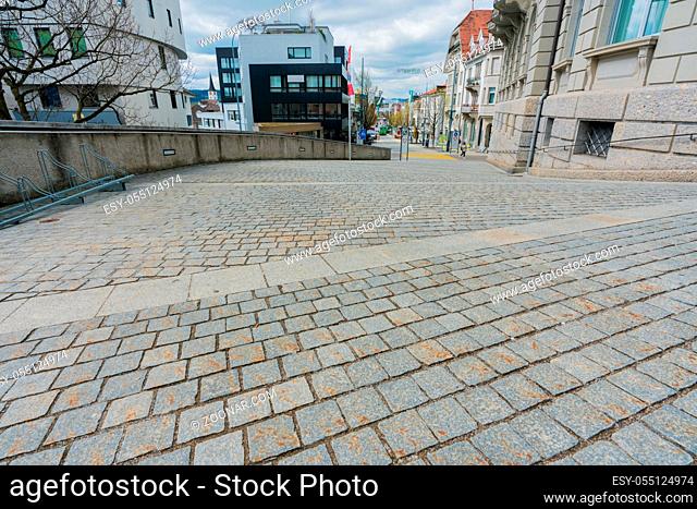 Wil, SG / Switzerland - April 8, 2019: cobblestone road leading from the old town of Will down into the new city with traffic and people at the intersection...
