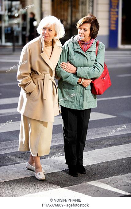 Woman helping elderly woman crossing the street