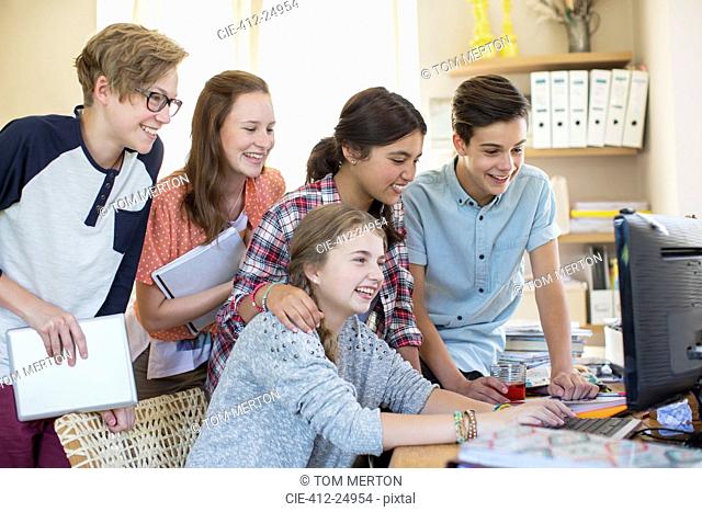 Group of teenagers using together computer in room