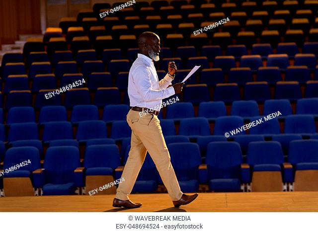 Businessman practicing and learning script while walking in the auditorium