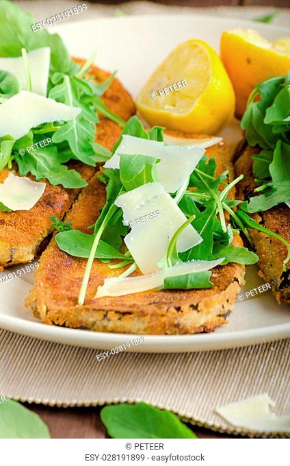 Fried breaded eggplant with salad of arugula topped with parmesan cheese