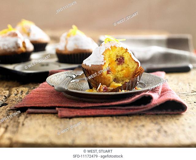 An orange and cranberry muffin with a bite missing