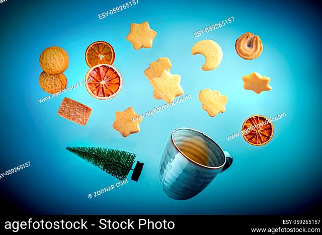 Danish butter cookies, a cup of tea and a Christmas tree, flying on a dark blue background. A creative Christmas banner design