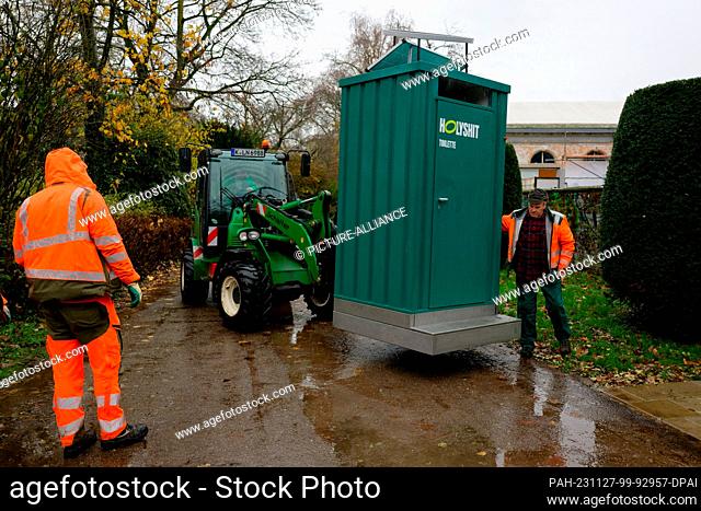 27 November 2023, North Rhine-Westphalia, Cologne: The ""Holy Shit"" dry toilet is brought to its place in the Volksgarten by employees of the City of Cologne