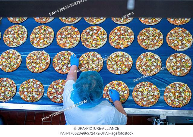 Employees cover pizza crusts with vegetable pieces in the pizza factory of the Dr. Oetker company in Wittenburg, Germany, 23 May 2017