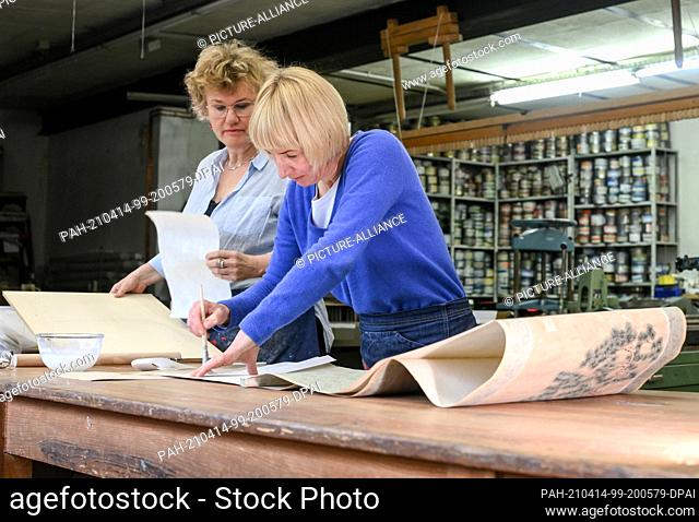 13 April 2021, Berlin: Assortment bookbinder Frauke Grenz (l) and bookbinder Julia Flögel work on restoring a Chinese scroll painting in their paper workshop in...