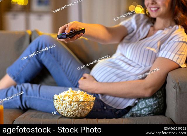 pregnant woman with remote control watching tv