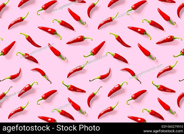 Creative background made of red chili or chilli on pink backdrop. Minimal food backgroud. Red hot chilli peppers background, not pattern