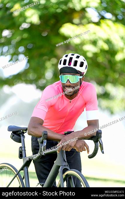 Young cyclist leaning on bicycle in park