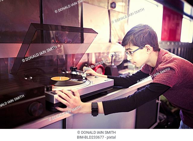 Mixed Race boy playing vinyl record on turntable