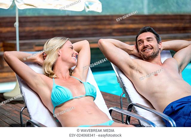 Couple talking while relaxing on a sun lounger