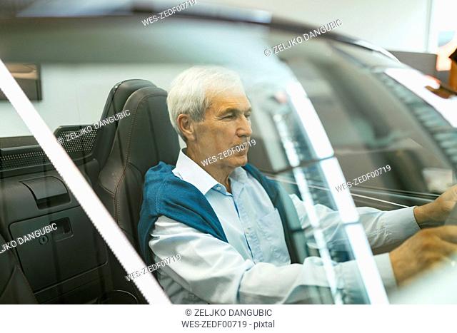 Senior man testing convertible in car dealership