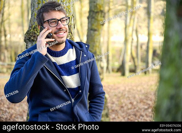 Smiling man, talking on mobile phone in an autumn park