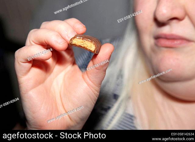 Obese woman holding a piece of chocolate with a peanut butter filling