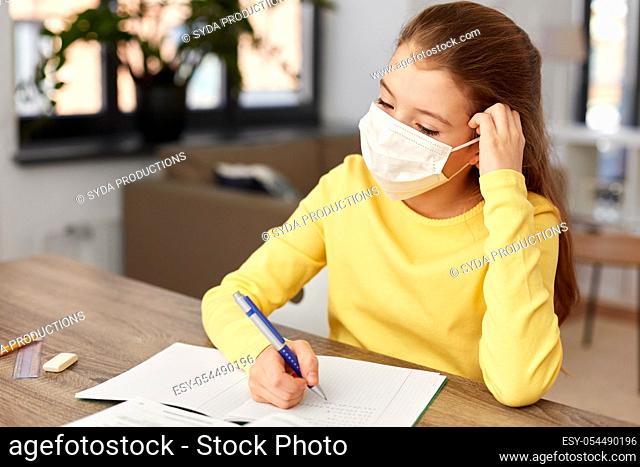 bored sick girl in medical mask learning at home