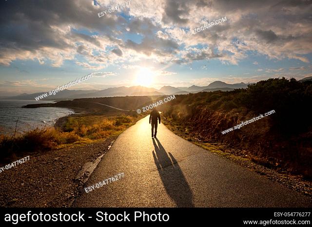 Scenic road in the mountains. Travel background. Man going on sunrise background
