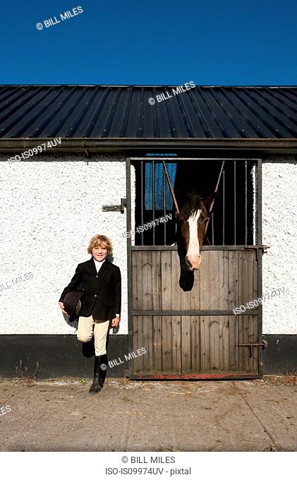 Boy standing by horse stables