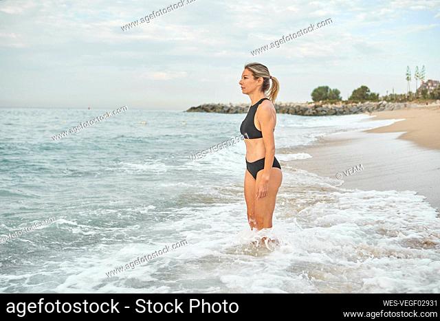 Woman admiring view while standing in water at beach