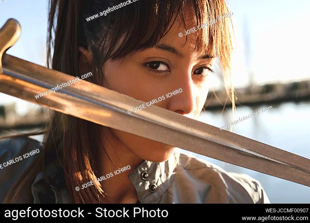 Female athlete staring with intense look practicing sword