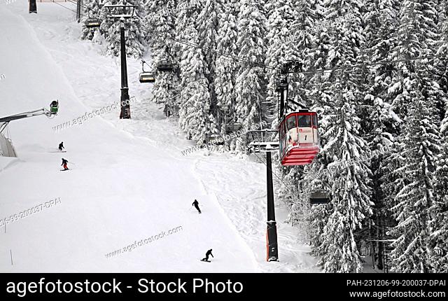 06 December 2023, Saxony, Oberwiesenthal: Skiers ski under the suspension railroad. Saxony's largest alpine ski area started the season on the same day