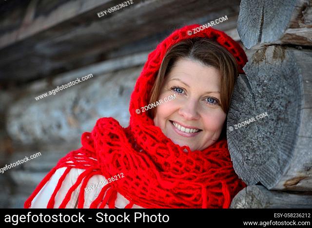 The Russian woman in a shawl warms hands near an izba