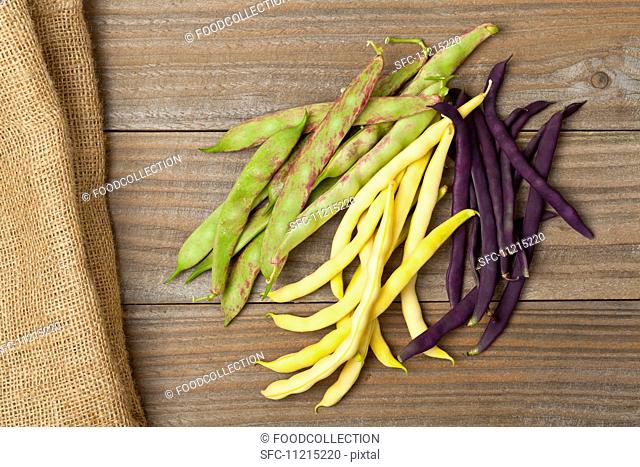 Wax beans, scarlet runner beans and blue French beans on a wooden table
