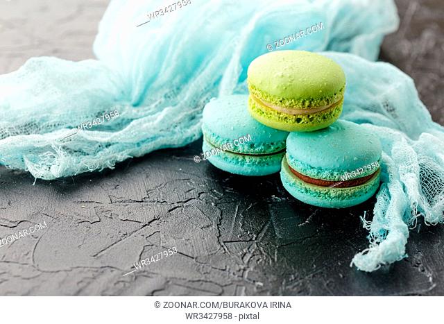 Classic French Macaroon cookies blue and green on black concrete background