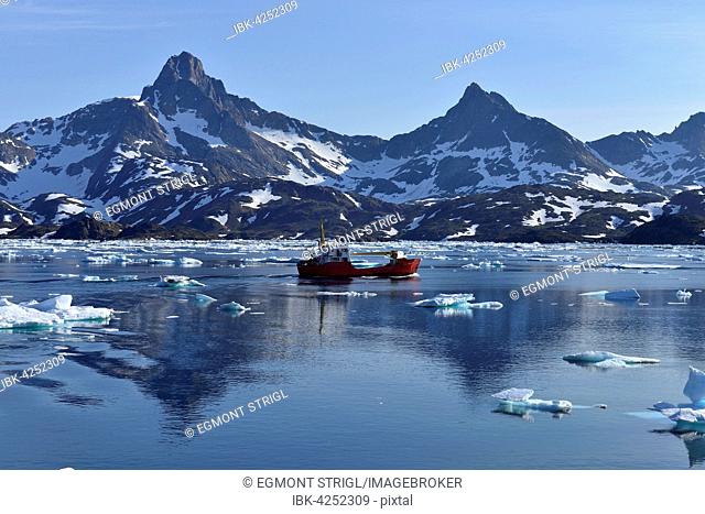Red freighter cruising through Kong Oscars Havn, Ammassalik Island, Kalaallit Nunaat, East Greenland