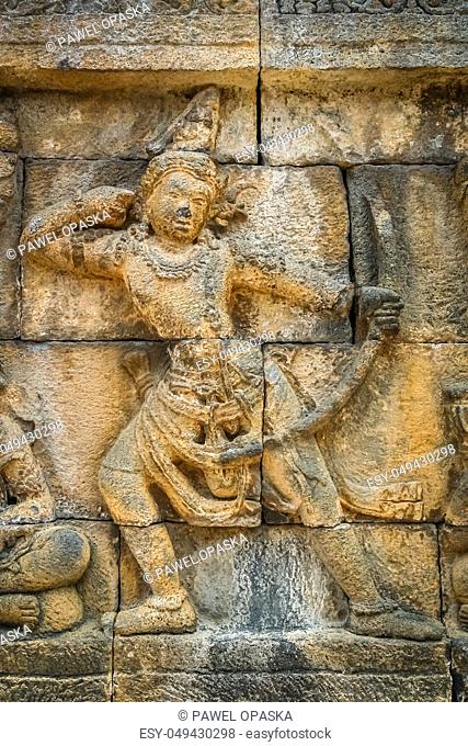 Small figure of a female archer carved on the wall in the Borobudur temple in Java, Indonesia