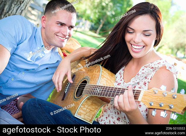 Happy Mixed Race Couple at the Park Playing Guitar and Singing Songs