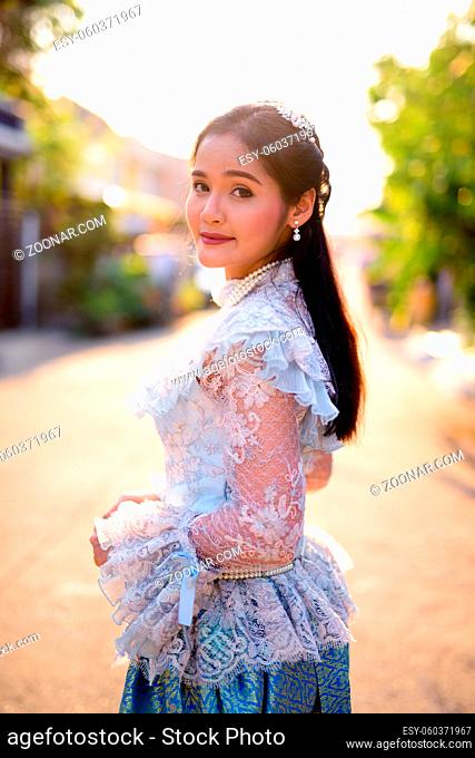 Portrait of young beautiful Asian woman wearing Thai traditional clothes outdoors