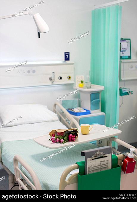Flowers on tray over hospital bed in vacant hospital room