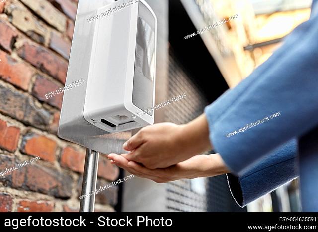 close up of woman at dispenser with hand sanitizer