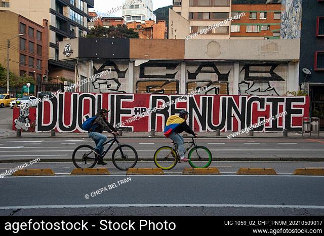 Cyclists pass in front of a mural against president Ivan Duque that reads ""President Duque QUIT"" as LGTB+ and Trans communities lead demonstrations as...