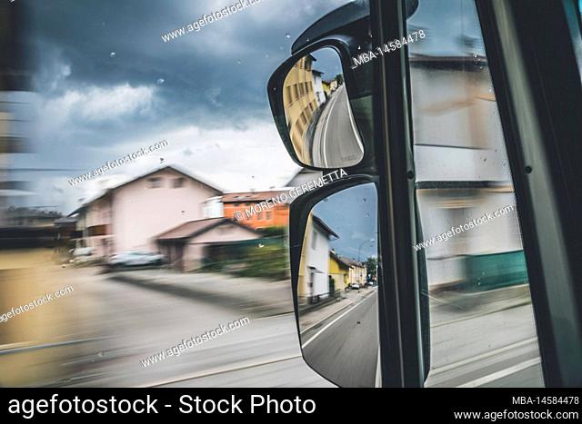 View of the road from the cab of a moving truck through the glass and rear view mirror